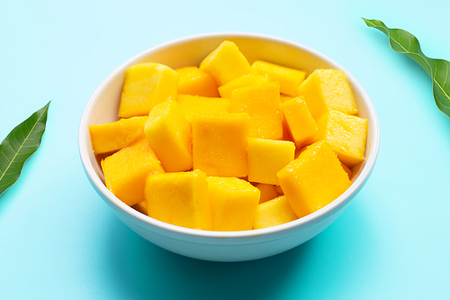 Tropical fruit, Mango cube slices in white bowl on blue background.