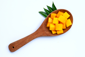 Sliced ripe mango cubes on wooden spoon on white background.