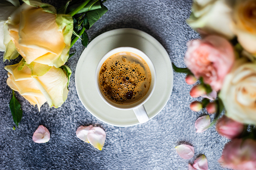 Coffee drink concept with cup of americano and roses on concrete background with copy space