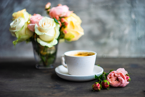 Coffee drink concept with cup of americano and roses on concrete background with copy space