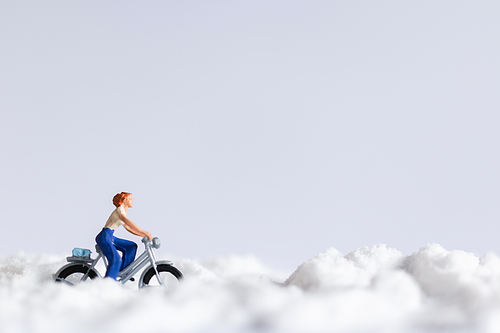 Miniature people : Travelers riding a bicycle on snow , winter background concept