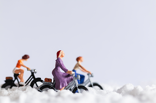 Miniature people : Travelers riding a bicycle on snow , winter background concept