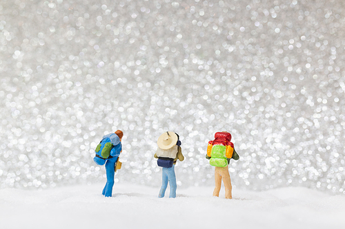 Miniature people: backpacker walking on snow background . Winter concept.