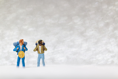 Miniature people: backpacker walking on snow background . Winter concept.