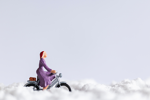 Miniature people : Travelers riding a bicycle on snow , winter background concept