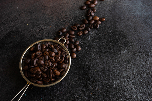 Strained full of coffee beans on dark stone background with copy space
