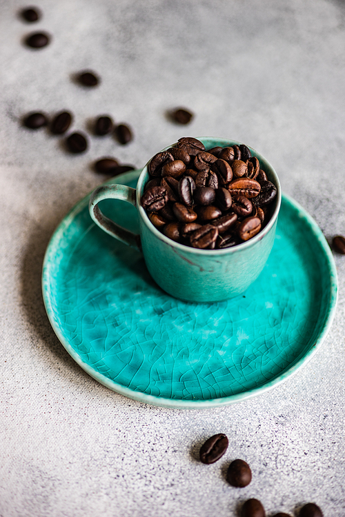 Cup full of organic coffee beans on stone background with copy space