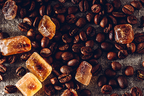 Roasted coffee beans and crystalline sugar scattered on cloth