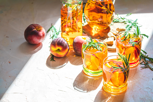 Glasses of sweet peach iced tea, Summer cold peach fizz cocktail with rosemary. Sunny light. Shallow depth of the field, close up, copy space for you text