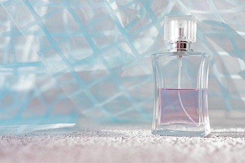 Perfume on a background of blue fabric . Smell. Aromatherapy. The choice of fragrance. A bottle of perfume. Copy space