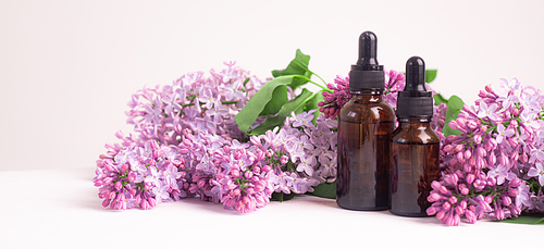 A bottle for cosmetic oil and lilac branches . Cosmetology. Cosmetic oil for the skin. An article about skin care. Lilac branch