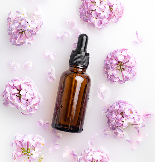 A bottle for cosmetic oil and lilac branches . Cosmetology. Cosmetic oil for the skin. An article about skin care. Lilac branch