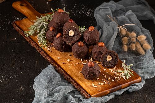 Dark chocolate truffles with hazelnuts over wooden cutting board.
