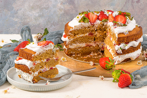 Strawberry cake, strawberry sponge cake with fresh strawberries and sour cream on a kitchen countertop.