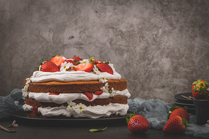 Strawberry cake, strawberry sponge cake with fresh strawberries and sour cream on a kitchen countertop.