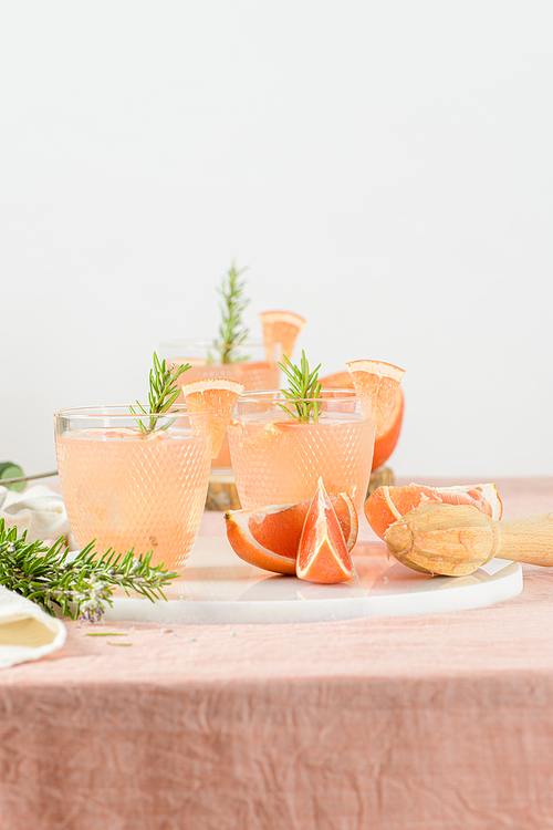 Grapefruit juice with rosemary in glasses on the table. Refreshing summer cocktail.