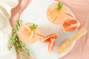 Grapefruit juice with rosemary in glasses on the table. Refreshing summer cocktail.