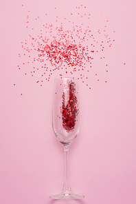 Flat lay of Celebration. Champagne glass with colorful party streamers on pink background.
