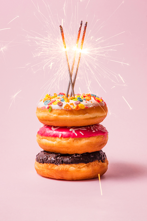 Delicious donuts for birthday on pastel pink background.