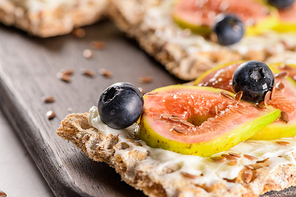 Canape or crostini with multigrain  crispread with cream cheese and fresh fig slices on a wooden board. Delicious appetizer ideal as an aperitif.