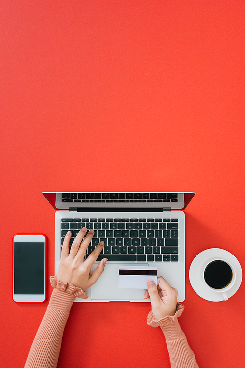 Woman using modern laptop at color table, top view