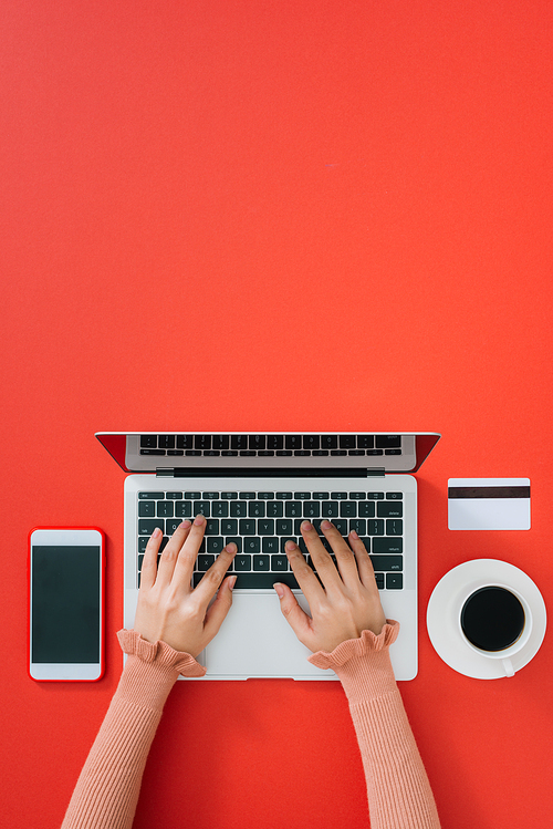 Woman using modern laptop at color table, top view