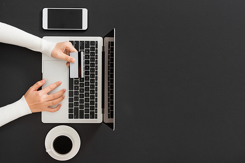 Female hand inserts data into the notebook and holding credit card