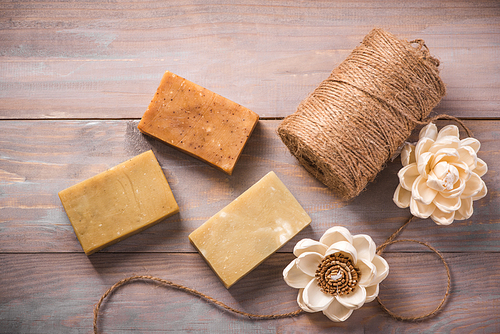 Natural soap with dried flowers on wooden background.