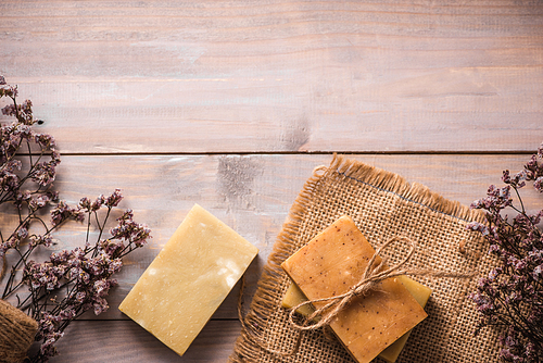Natural soap with dried flowers on wooden background.