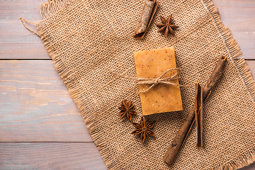 Handmade soap with cinnamon and anise star on wooden background.