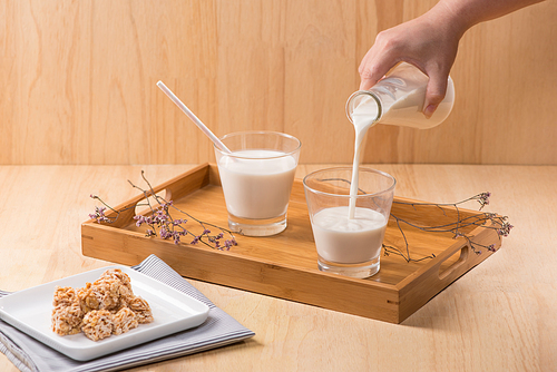 Dairy products. A bottle of milk and glass of milk serve with almond candies on a wooden table.