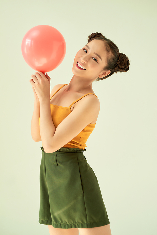 Portrait of attractive lovely gilr holding air balloon against light background.