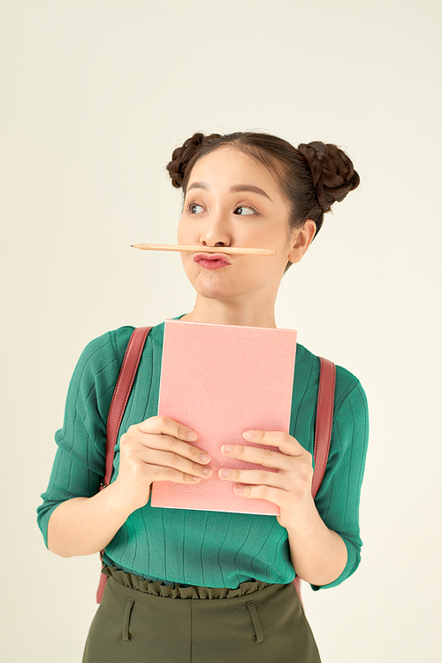 Young teenage student freaking out and holding her pencil between nose and lips as moustache looking funny and naughty