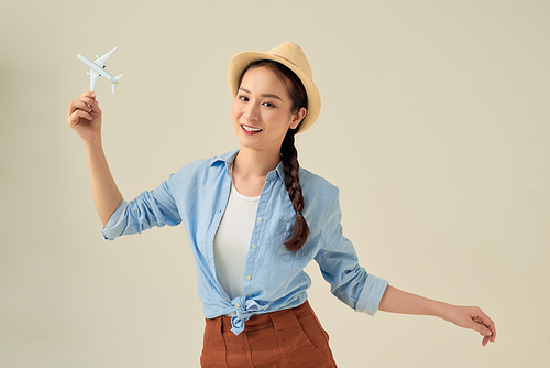 Portrait of young happy woman holding jet aircraft on white background. Advertisement banner for transport companies