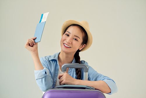 Portrait of a happy young woman holding traveling tickets and passport isolated over light background