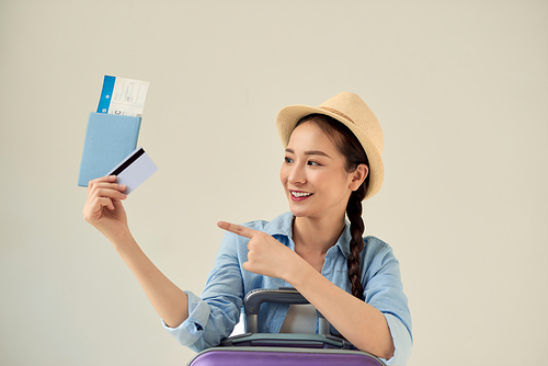 Beautiful young asian woman wear hat with showing credit card and passport and pointing to travel summer trip, girl in vacation with payment finance on card.