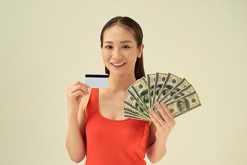 Young woman with money and credit card on gray background