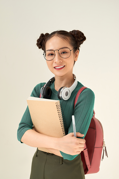 Asian student woman wearing backpack holding notebook over isolated white background with a happy face standing and smiling with a confident smile showing teeth