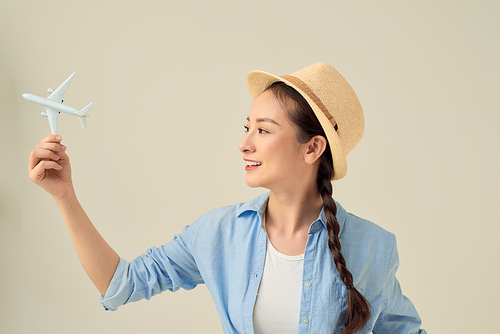 Closeup portrait of beautiful woman in straw hat holding airplane model in hand, dreaming about holidays