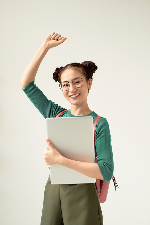 portrait of a female student holding a laptop and gesturing happiness with raised arms isolated on white