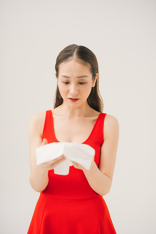 Woman with a cold blowing her runny nose with tissue.