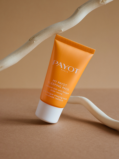 Skin moisturizer cosmetic care night mask Payot with orange package on shiny beige background.