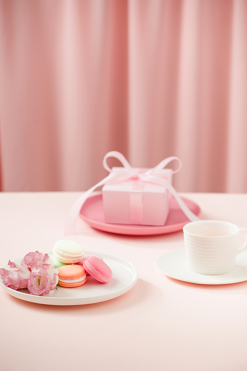 Happy woman/mothers Day image of a coffee or tea cup and lisianthus flower with macaroon and gifts beside on drapes of pink.