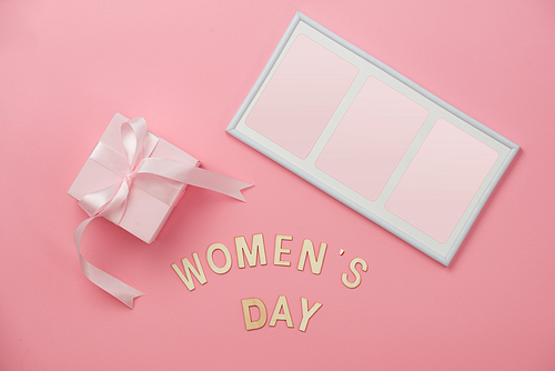 Women's day concept, happy women's day, international women's day. Womans day text wooden, pink gift with picture frame on coral background