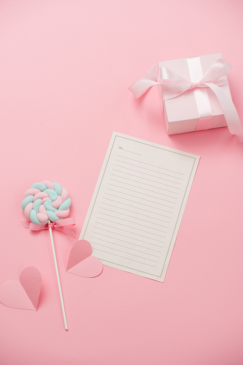 A white sheet of paper for message to loved one, candy on pink background. Happy womans day concept. Mock up