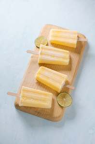 Pineapple popsicles on a marble paddle board. Top view over a blue wood background.