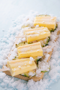 Yellow fruit popsicles on a plate. Top view over a blue wood background.