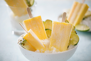 Some homemade Pineapple Popsicles (selective focus) on a rustic background