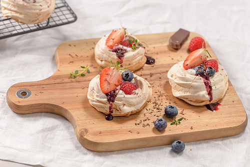 Small pavlova cakes with fresh raspberries and blueberries.
