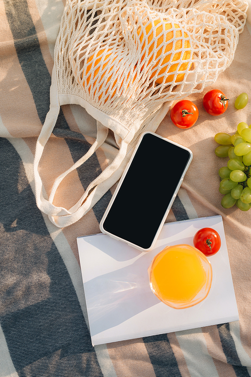 Fruit net bag with flip flop, phone, notebook on the plaid